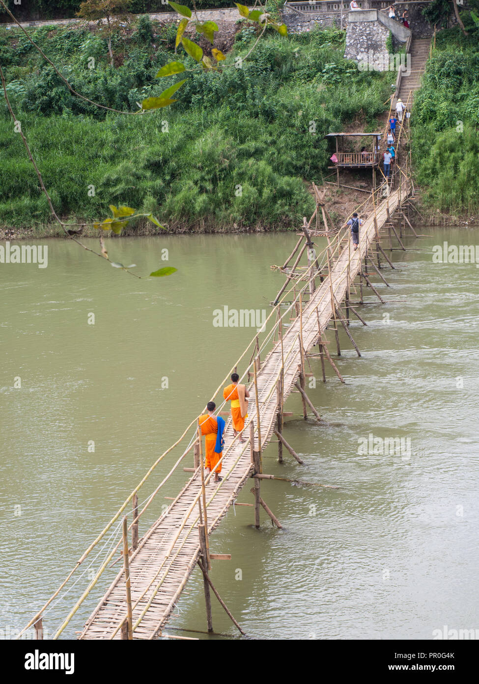 Orange gekleideten buddhistischen Mönche Überqueren einer Brücke aus Bambus, Luang Prabang, Laos, Indochina, Südostasien, Asien Stockfoto