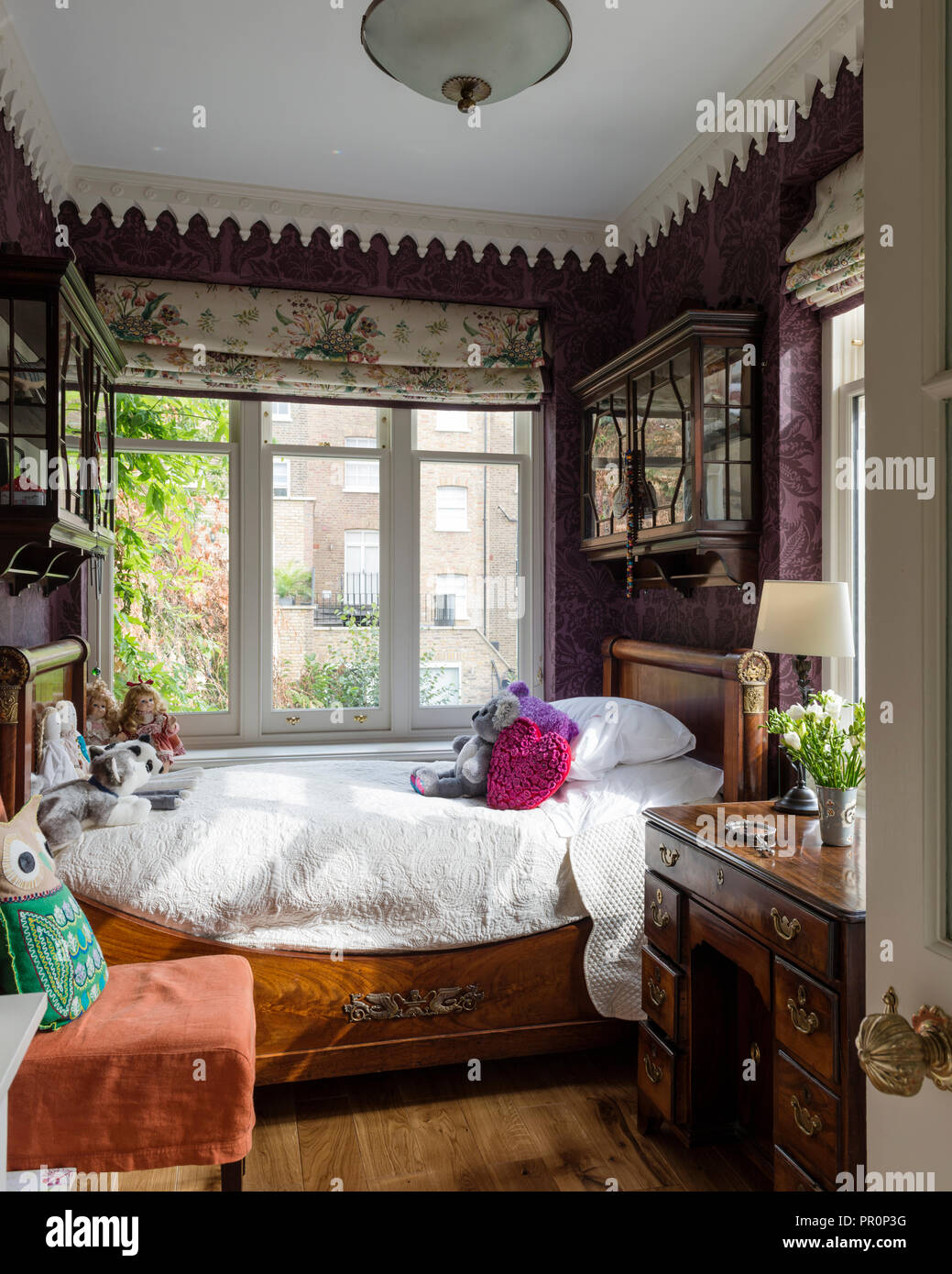 Antikes Holzbett unter Fenster mit Blumenmuster blind ist in aurikel von Colefax und Fowler. Stockfoto