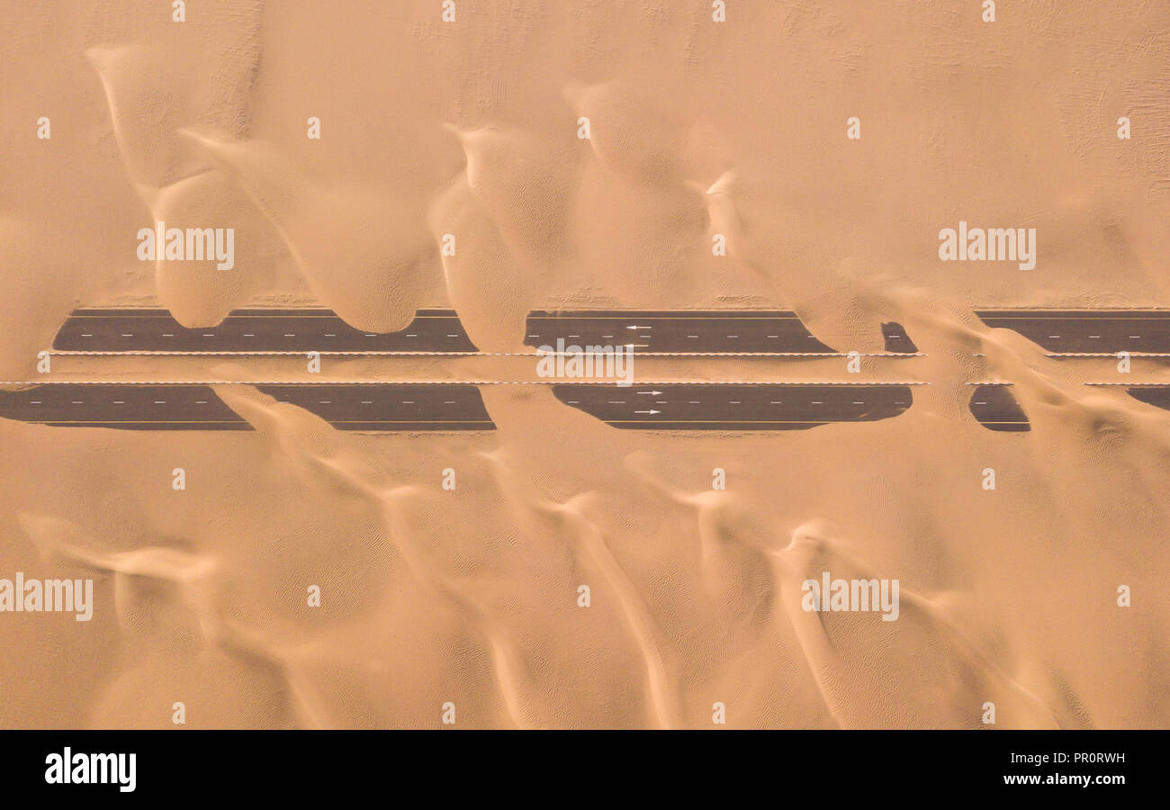 Luftaufnahme von einer Wüste Straße von Sanddünen, fotografiert von einer Drohne bei Sonnenaufgang. Dubai, VAE. Stockfoto
