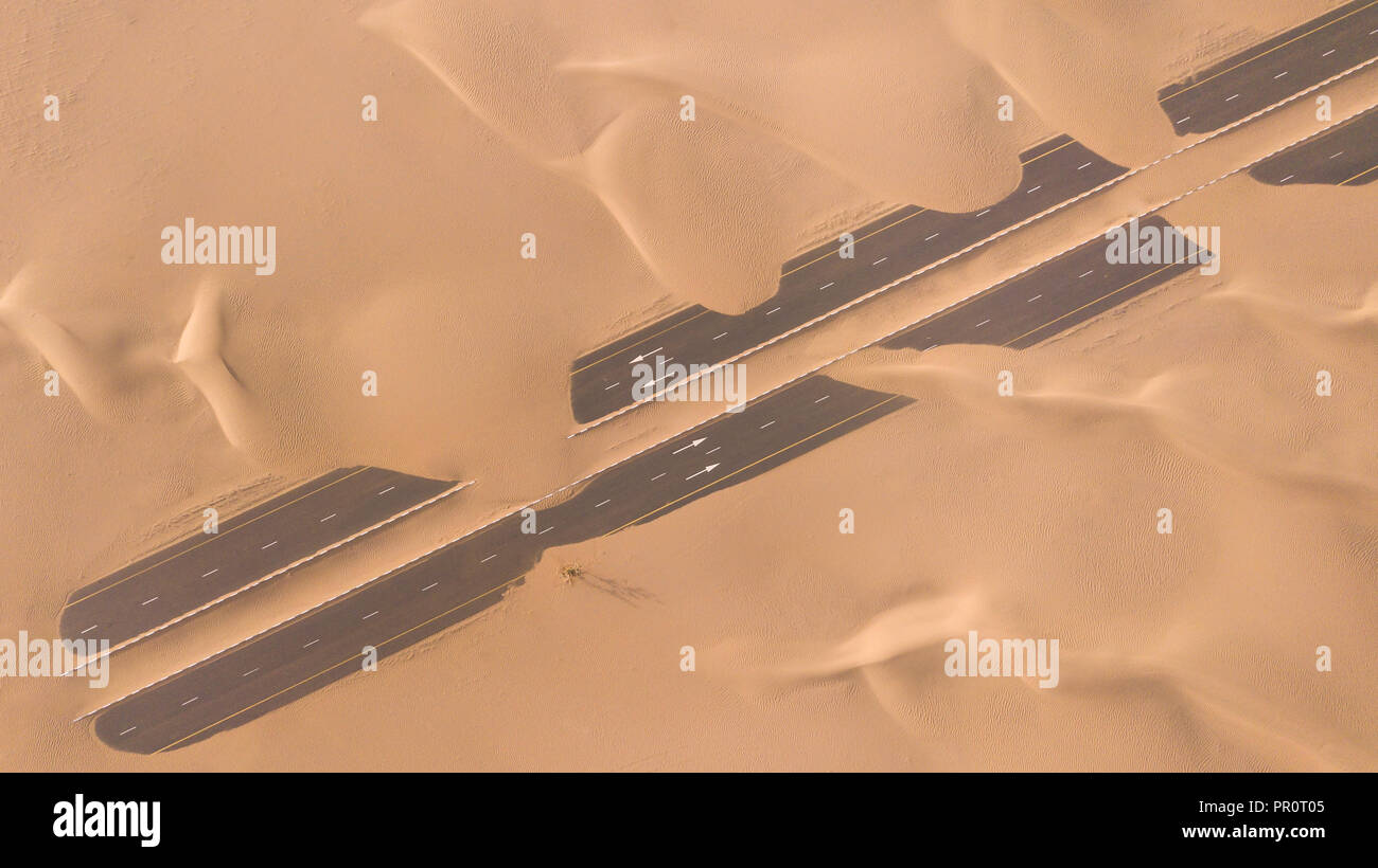 Luftaufnahme von einer Wüste Straße von Sanddünen, fotografiert von einer Drohne bei Sonnenaufgang. Dubai, VAE. Stockfoto