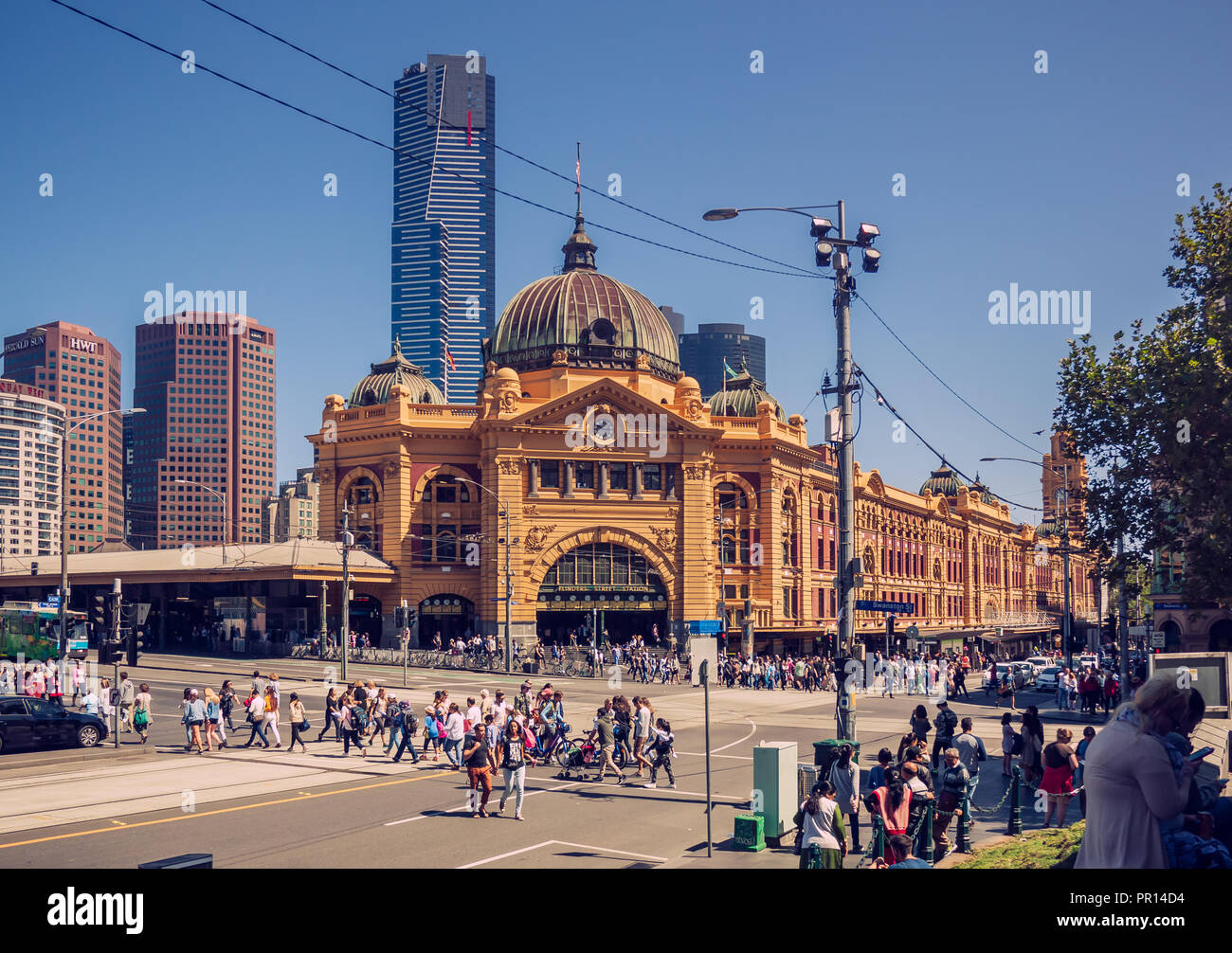 Die Menschen sind über die Straße vor dem Bahnhof Flinders Street in Melbourne, Australien. Es ist ein klarer Himmel. Stockfoto