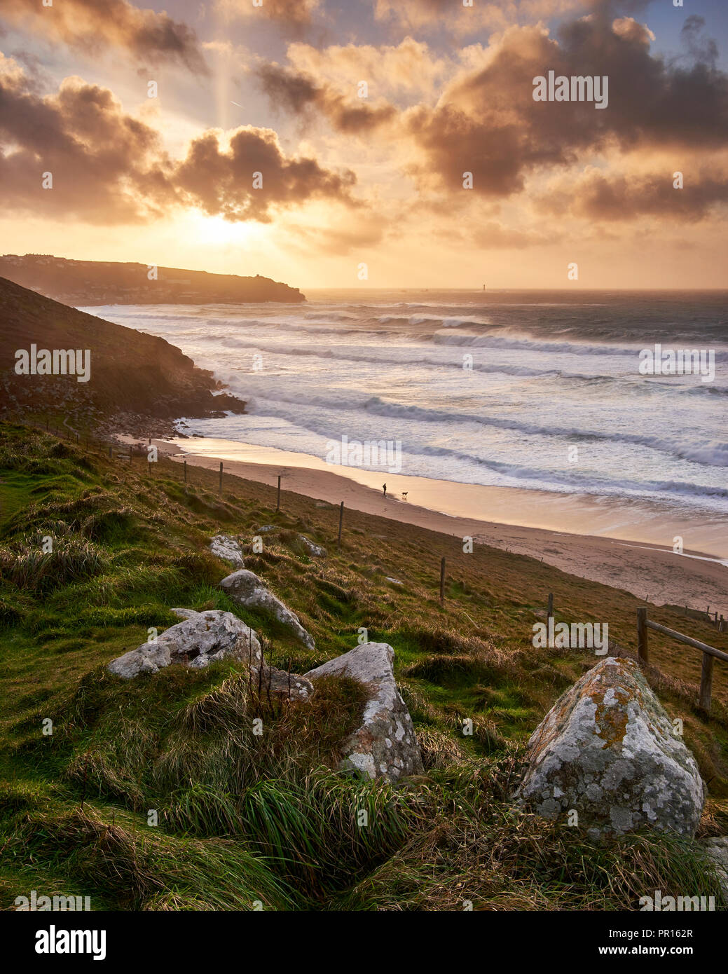 Ein winter Dog Walker Uhren die Wellen in einem Sturm am Strand in der Nähe von Gwenver Sennen in Cornwall, England, Großbritannien, Europa Stockfoto