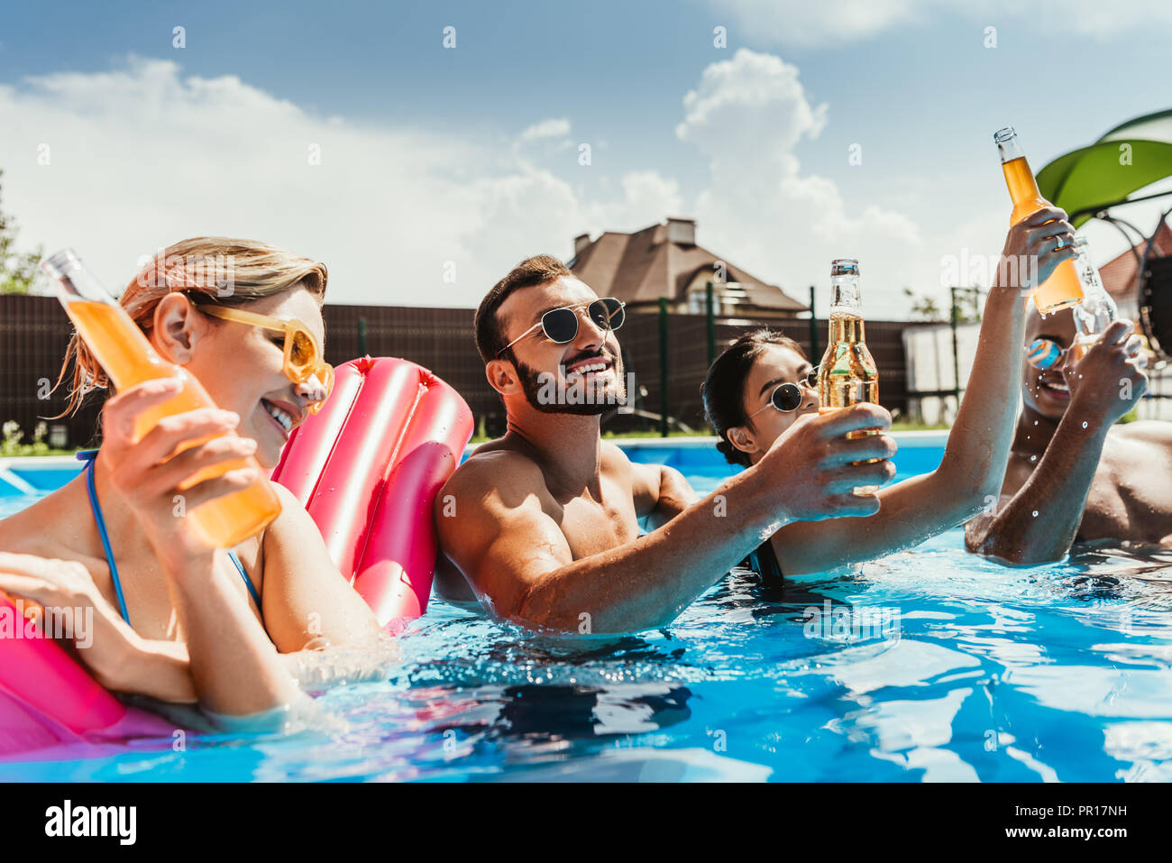 Multikulturelle Freunde mit Flaschen Bier im Pool mit aufblasbaren Matratze  Stockfotografie - Alamy