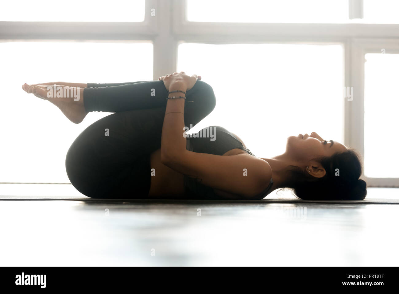 Junge sportliche Frau Üben Yoga, Knie zur Brust exercis Stockfoto