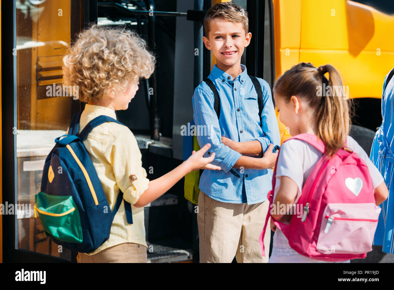 Adorable Schüler chatten in der Nähe der Schule Bus Stockfoto