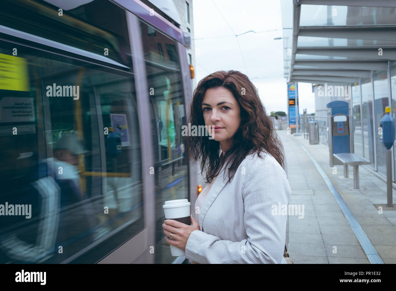 Geschäftsmann mit Kaffee Tasse stehen am Bahnhof Stockfoto