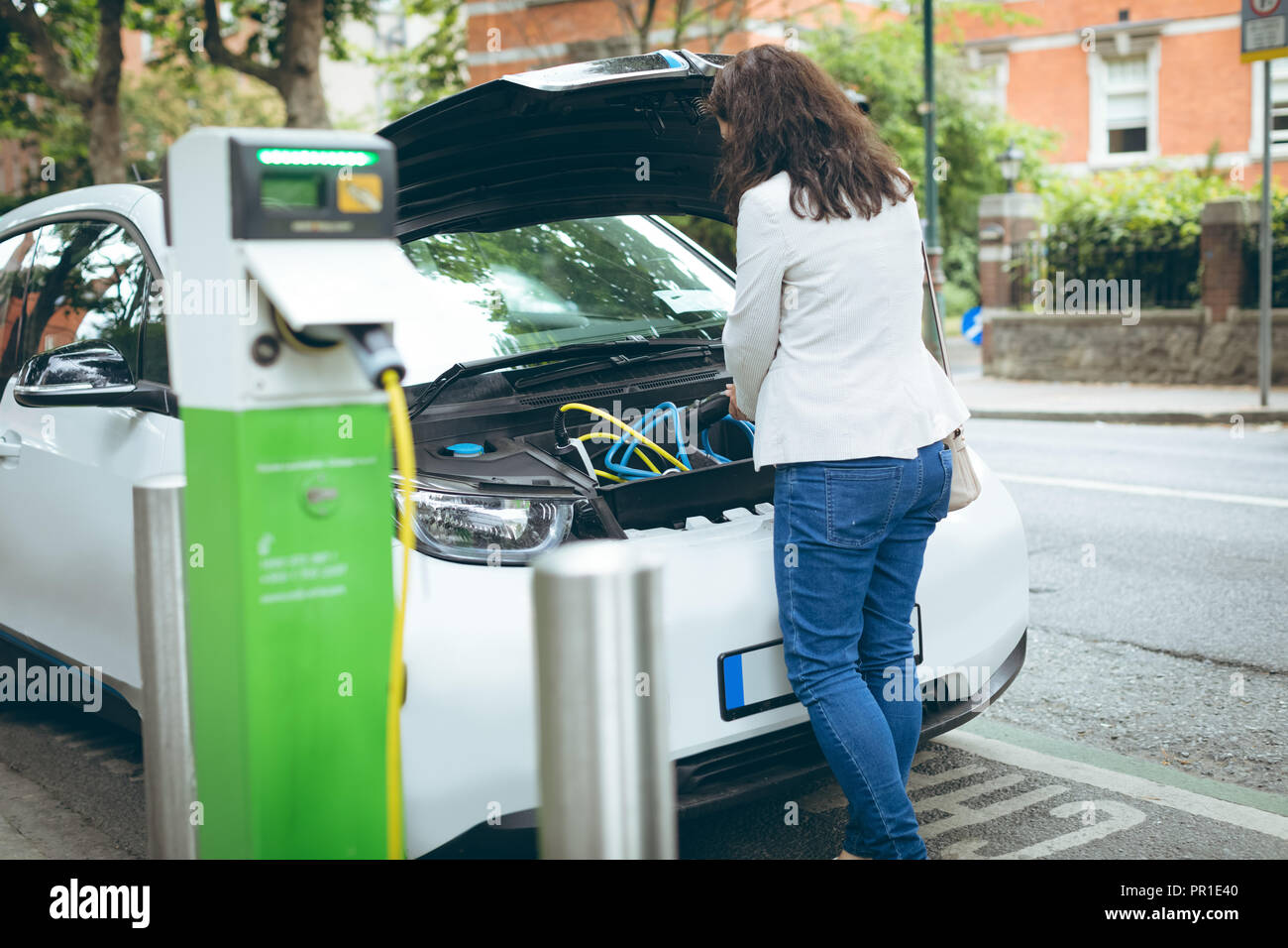 Geschäftsfrau laden Elektroauto an der Ladestation Stockfoto