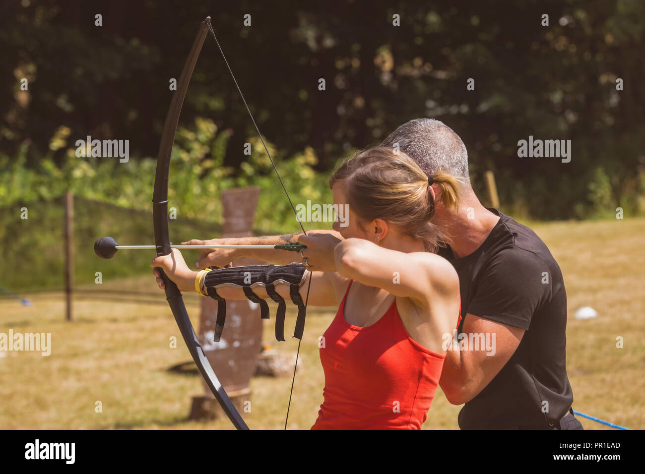 Trainer unterweisen Frau über Bogenschießen Stockfoto