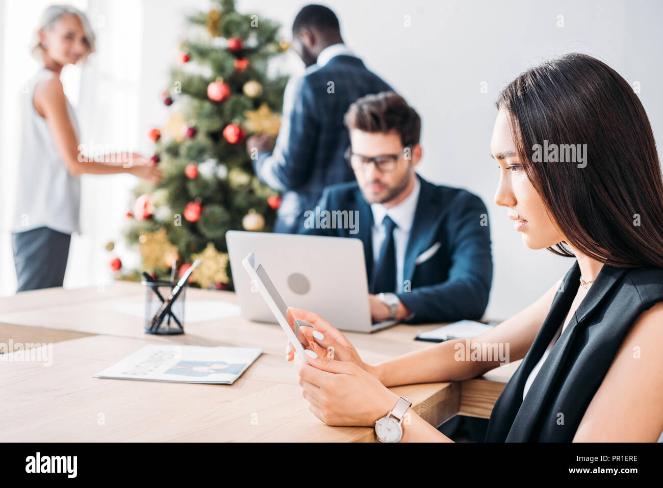 Asiatische Geschäftsfrau und Kollegen schmücken Weihnachtsbaum im Büro Stockfoto