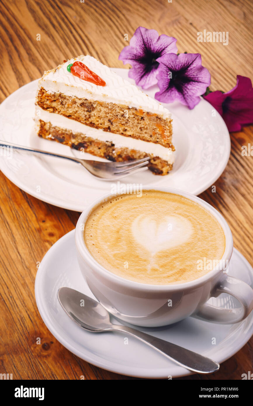Tasse Cappuccino mit leckeres Stück Karottenkuchen auf dem hölzernen Tisch Stockfoto