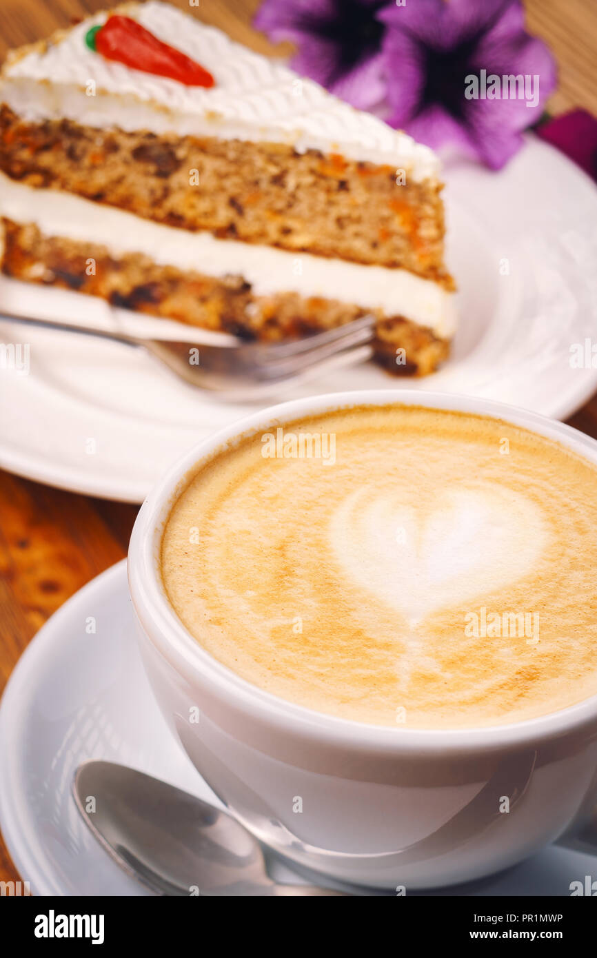 Tasse Cappuccino mit leckeres Stück Karottenkuchen auf dem hölzernen Tisch Stockfoto