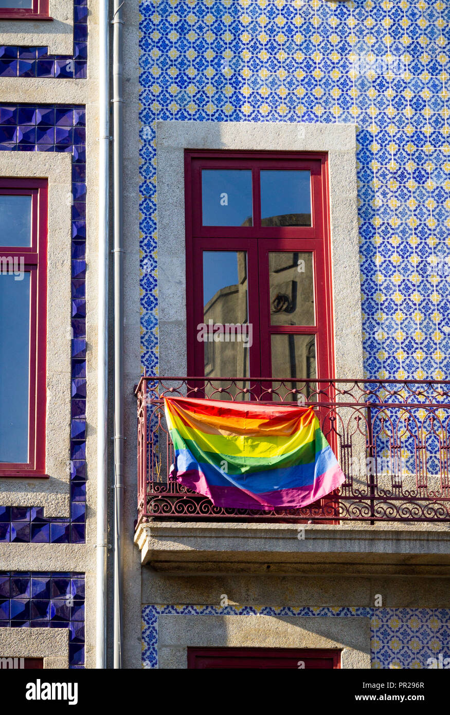 Eine LGBT-Flagge hängt auf dem Balkon von einem Gebäude mit gefliester Fassade. Stockfoto