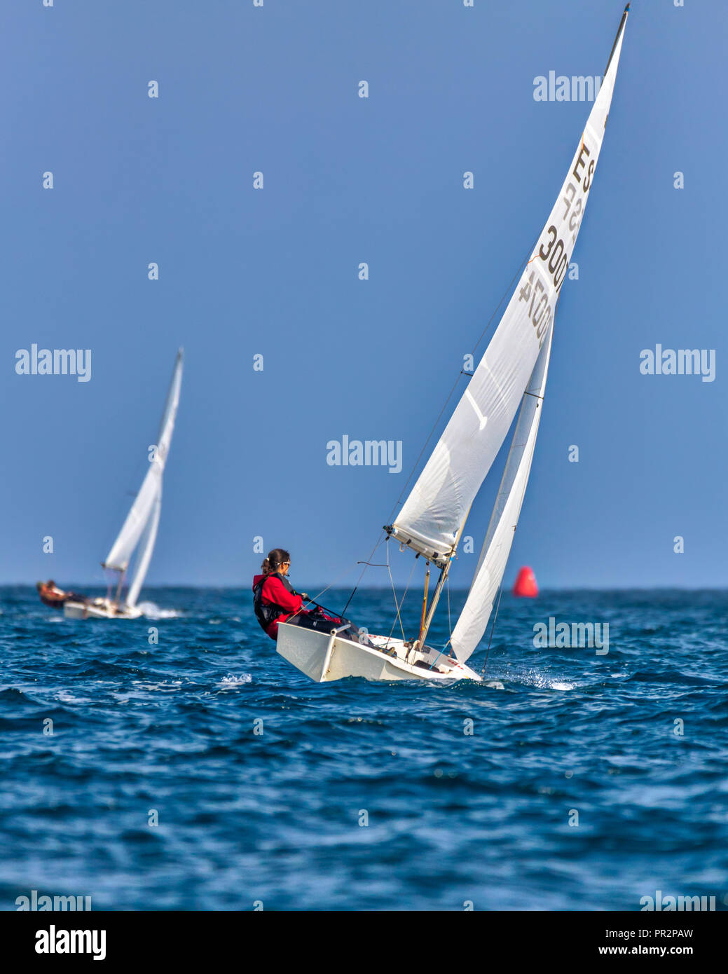 Wettbewerber auf dem blauen Mittelmeer racing einzelnen Finn Segelboote mit der roten Markierung drehen, um in der Ferne Stockfoto
