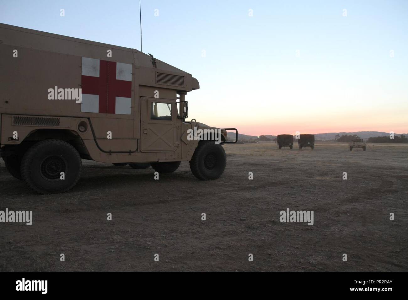 Ambulanzfahrzeuge, die zu der im Bereich der Medizinischen Gesellschaft (Asmc) vor der untergehenden Sonne auf eine der letzten Nächte des Globalen Medic Combat Support Training (CSTX) im Camp Roberts, Calif im Asmc neben die 332 medizinische Brigade, im Falle da abgesehen von der Premier health Support Provider auf die Combined Joint Task Force, die militärische Mitglieder aus der US-Armee Finden und Army Guard Reserve (AGR), Marine, Luftwaffe, Marine, zusammen mit militärischen medizinischen Fachleuten aus der Kanadischen Armee und Royal Saudi Arabien Land geltenden teilgenommen. Global Medic Stockfoto