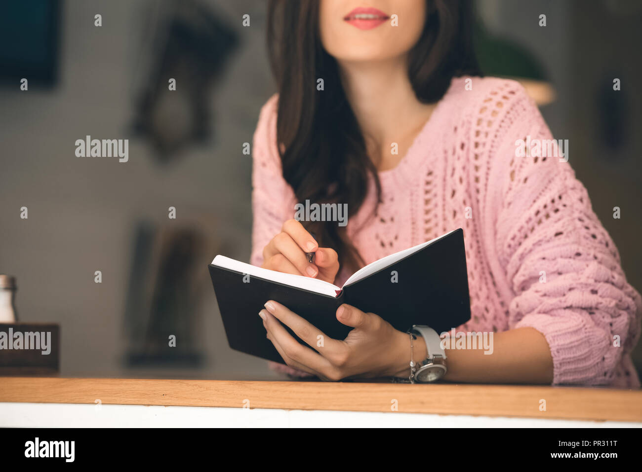 Teilweise mit Blick auf die Frau, die Noten im Lehrbuch am Tisch im Cafe Stockfoto