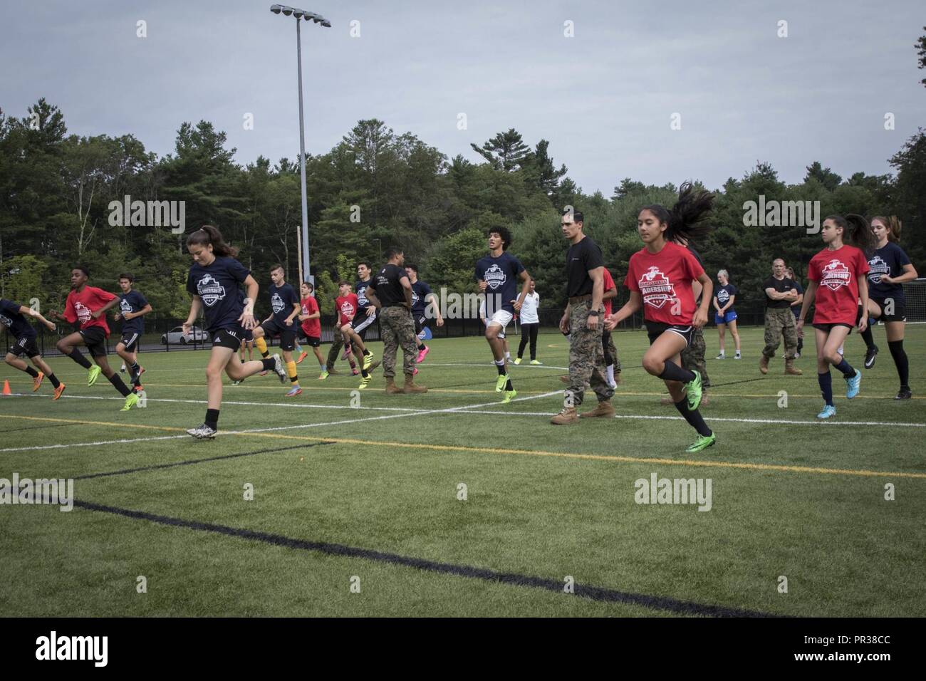 Us-Marines mit einziehenden Station Portsmouth laufen die Teilnehmer der Sport Leadership Academy - Boston Fußball-Programm über eine dynamische Warm-up Session in den Vordergrund tritt in Taunton, Massachusetts, 22. Juli 2017. Die Akademie ist ein kostenloses Programm, High School Athleten angeboten, ihre Fußball-Fähigkeiten und gewinnen Führung Wissen aus der lokalen Marine recruiters zu steigern. Stockfoto