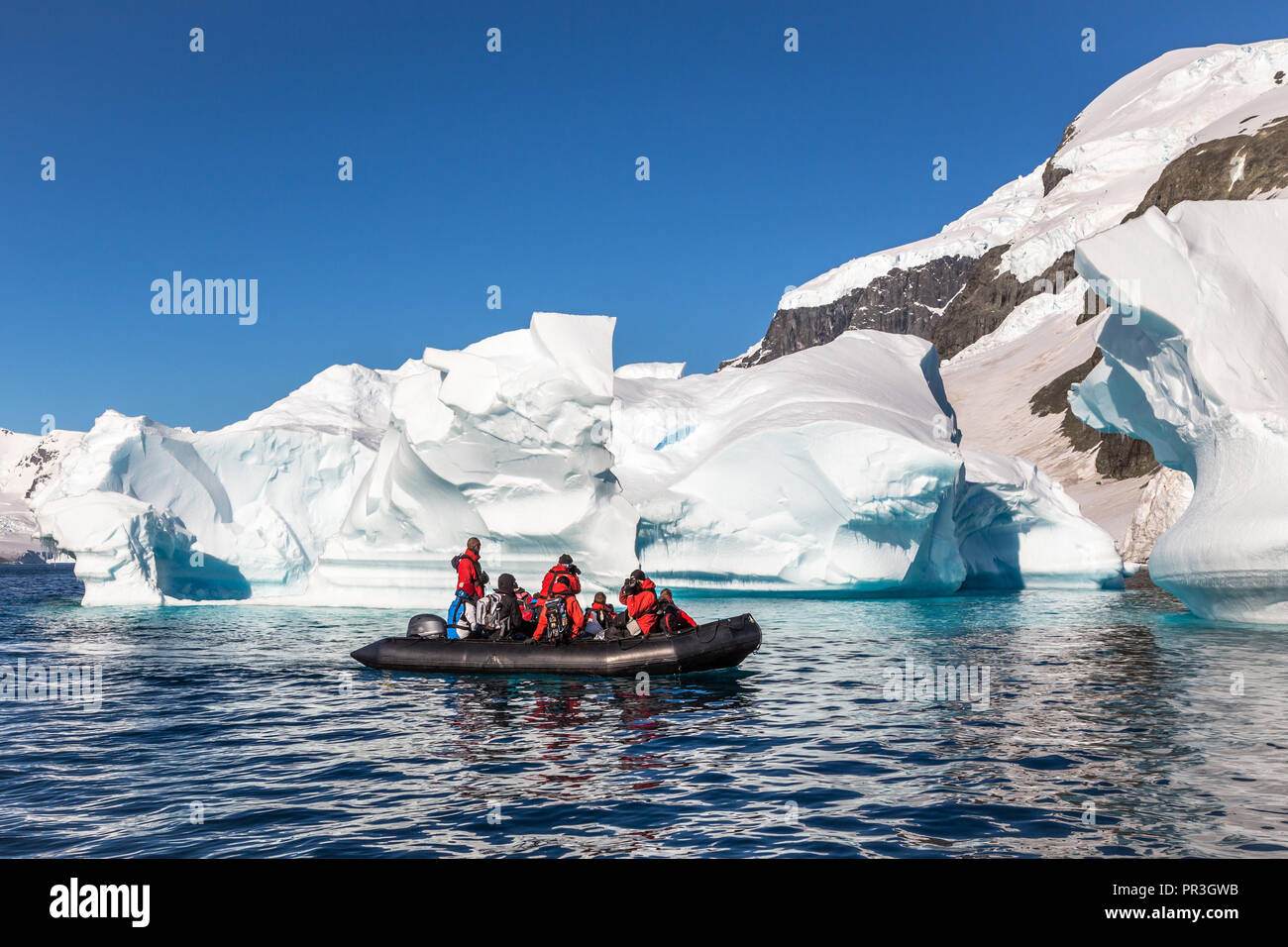 Boot voller Touristen riesige Eisberge in der Bucht in der Nähe von Cuverville Insel driften erkunden, Antarktische Halbinsel Stockfoto