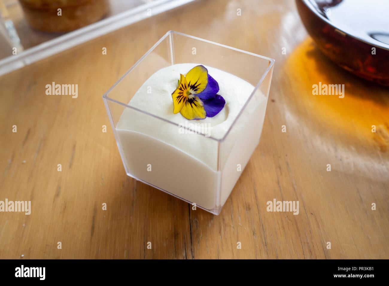 Frische Sahne in einem Glas mit einem blauen und gelben Blume Stockfoto