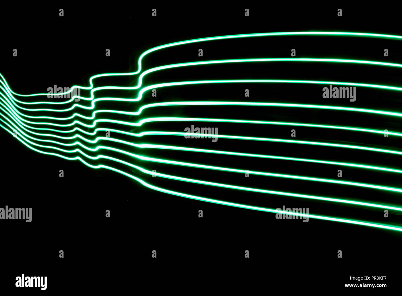 Lange Belichtung Licht Malerei Fotografie, parallelen Linien von lebendigen Grün verschwinden in der Ferne vor einem schwarzen Hintergrund Stockfoto