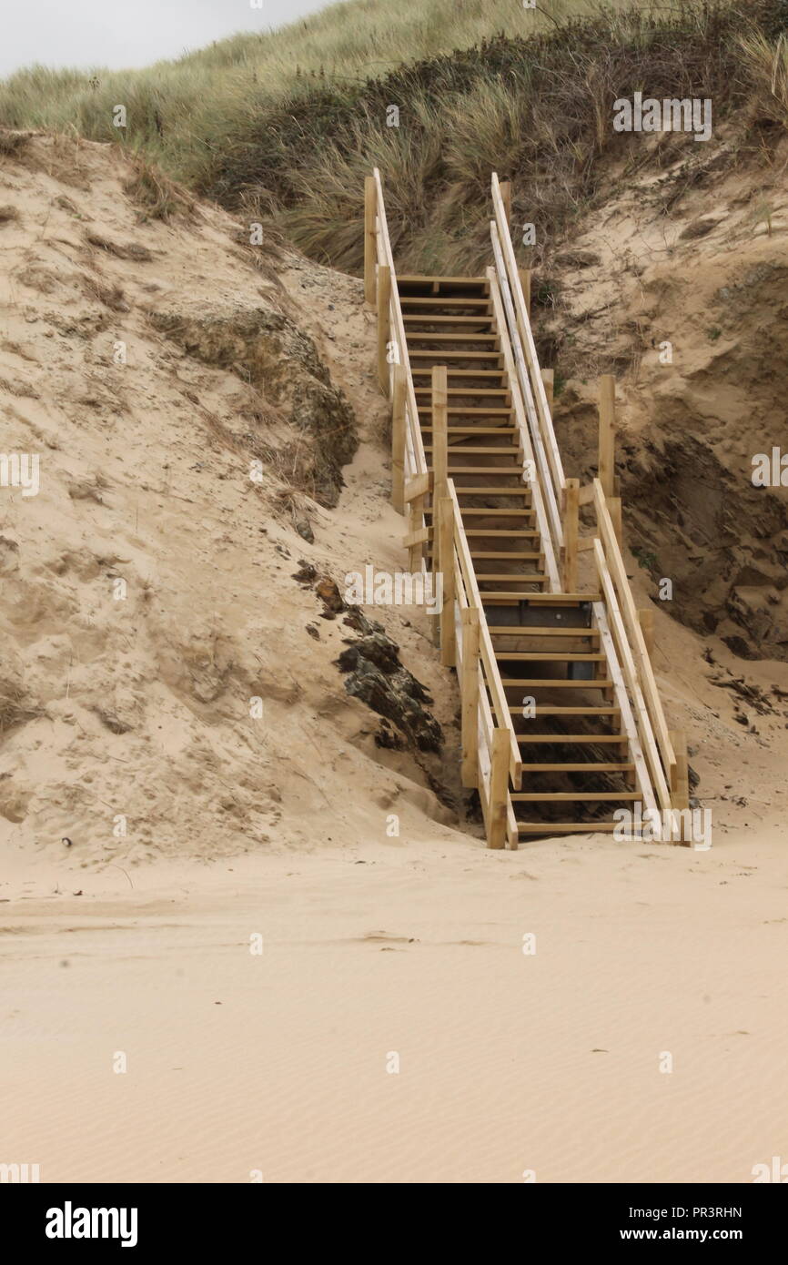 Eine Holztreppe auf einen Sandstrand führenden Stockfoto