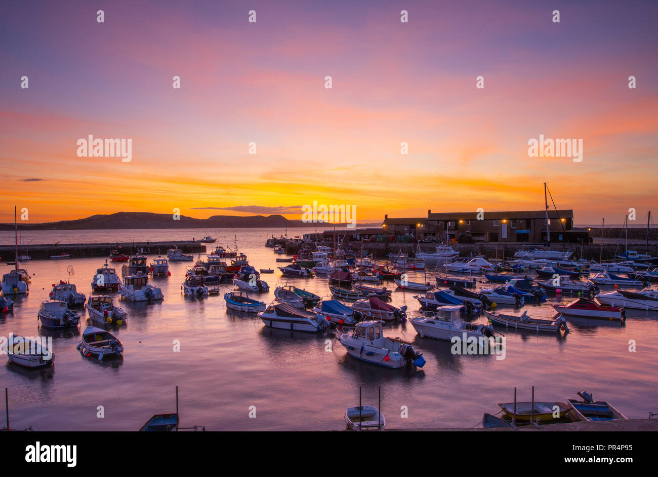 Lyme Regis, Dorset, Großbritannien. 29. September 2018. UK Wetter: der Himmel über dem Cobb Hafen glühen mit leuchtenden Farben zu Beginn eines sonnigen Tages in Lyme Regis. Credit: Celia McMahon/Alamy leben Nachrichten Stockfoto