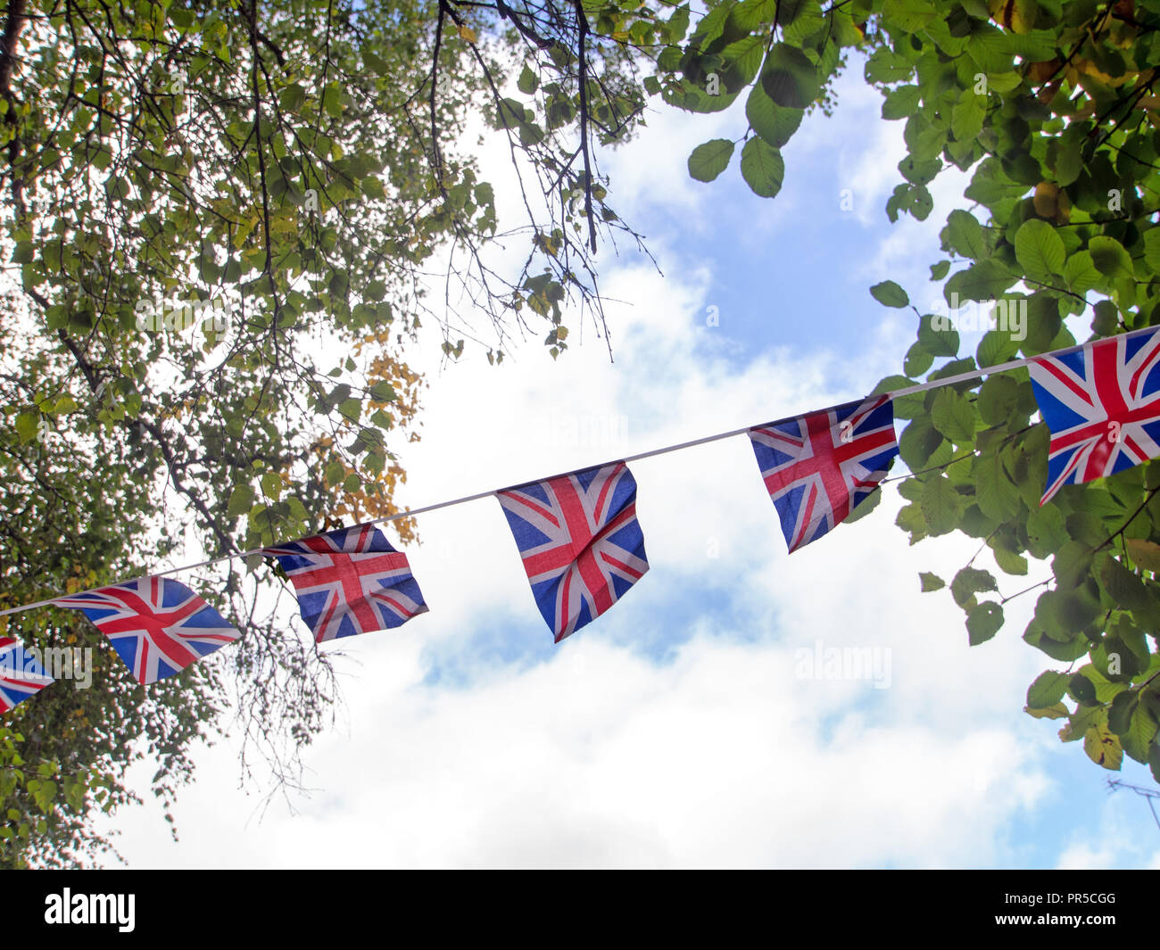 Rot, Weiß und Blau festliche bunting Fahnen gegen Himmel Hintergrund. Union Jack, UK Fahnen in den Wind. Brexit vielleicht. Stockfoto