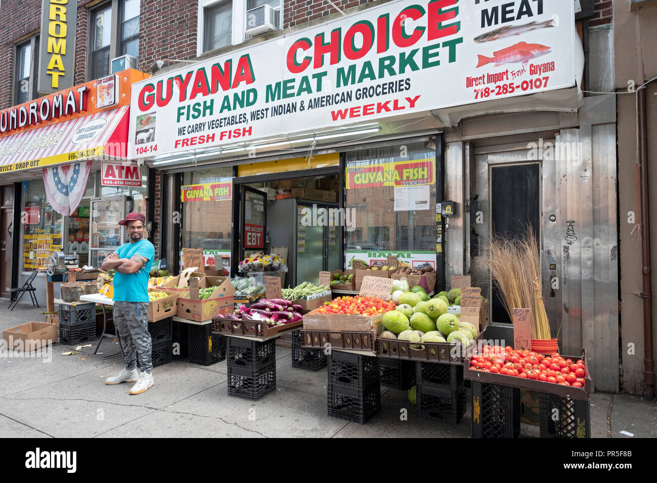 Ein Arbeitnehmer außerhalb des Guyana Wahl Fisch und Fleisch Markt auf Liberty Avenue in South Richmond Hill, Queens, New York City. Stockfoto