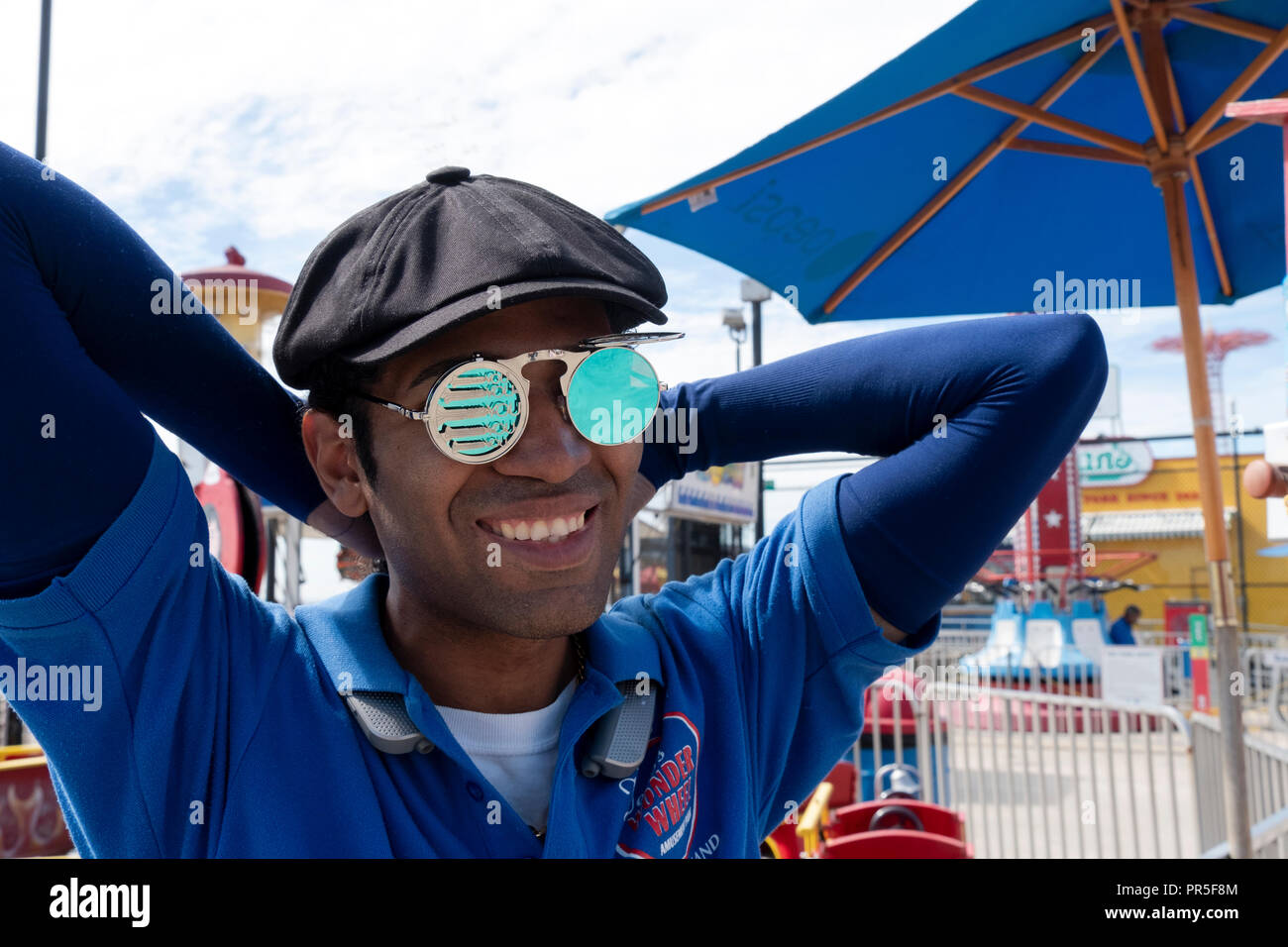 Ein Arbeiter bei Dino's Wonder Wheel Amusement Park tragen ungewöhnliche cyan Farbige Sonnenbrille, die sagen, dass die Crew." In Coney Island, Brooklyn, New York Stockfoto