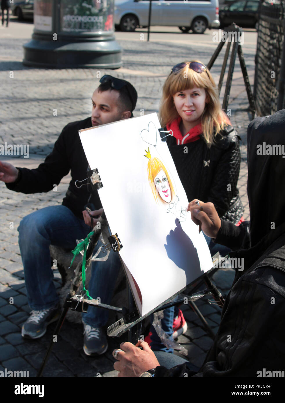 Eine Frau posiert für ein eher zwielichtige Gestalten Portrait von einem street artist in St. Petersburg in Russland. Stockfoto