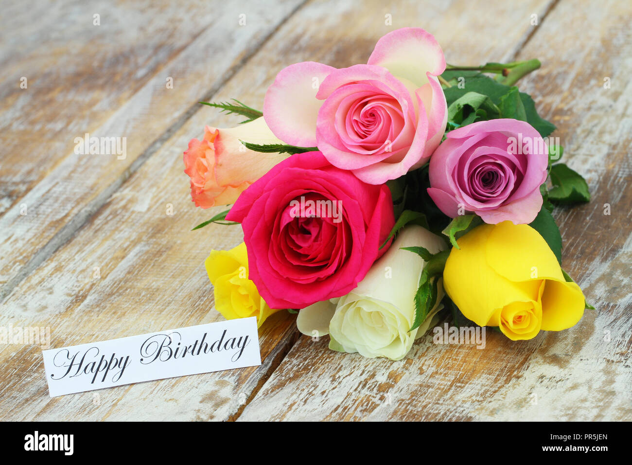 Happy Birthday Karte mit bunten Blumenstrauß aus Rosen auf rustikalem Holz Stockfoto