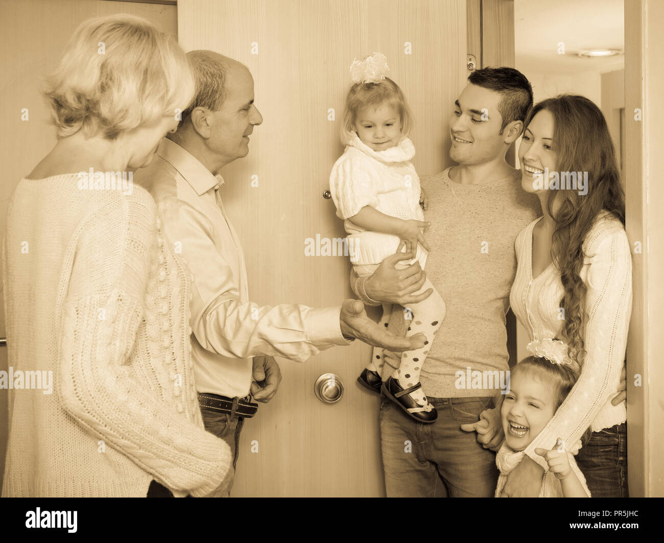 Positive junge Familie mit zwei Töchtern, die Großeltern zu besuchen Stockfoto