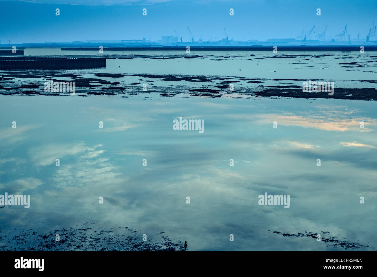 Der Himmel ist in der Lagune wider, eine industrielle Hafen im Hintergrund. Stockfoto