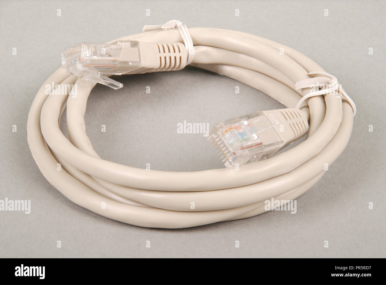 Patchkabel grau Netzwerkkabel mit RJ45-Stecker, auf einem grauen Hintergrund isoliert Stockfoto