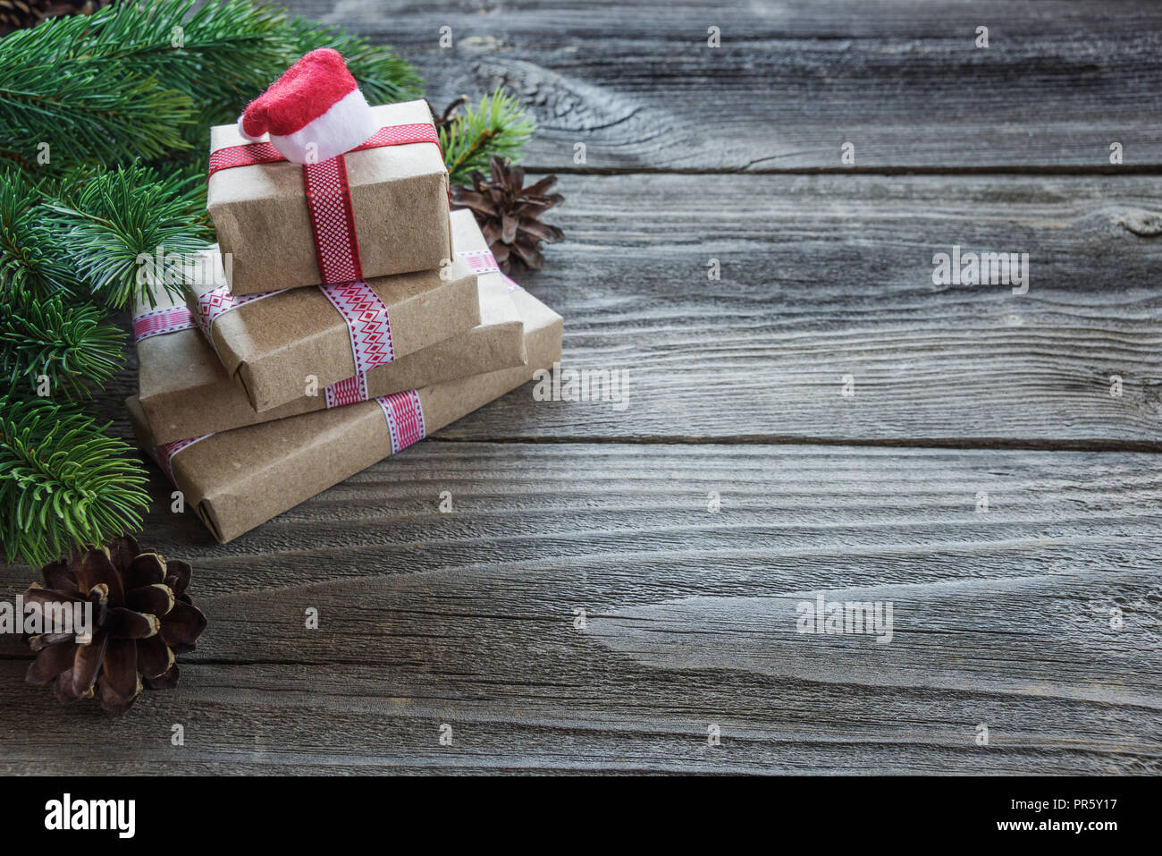Weihnachten Zusammensetzung der Tannenzapfen, Blätter, Zweige Fichte und Stapel von geschenkboxen mit Weihnachtsmann-mütze auf dem Hintergrund der alten unlackierte Holz; mit c Stockfoto