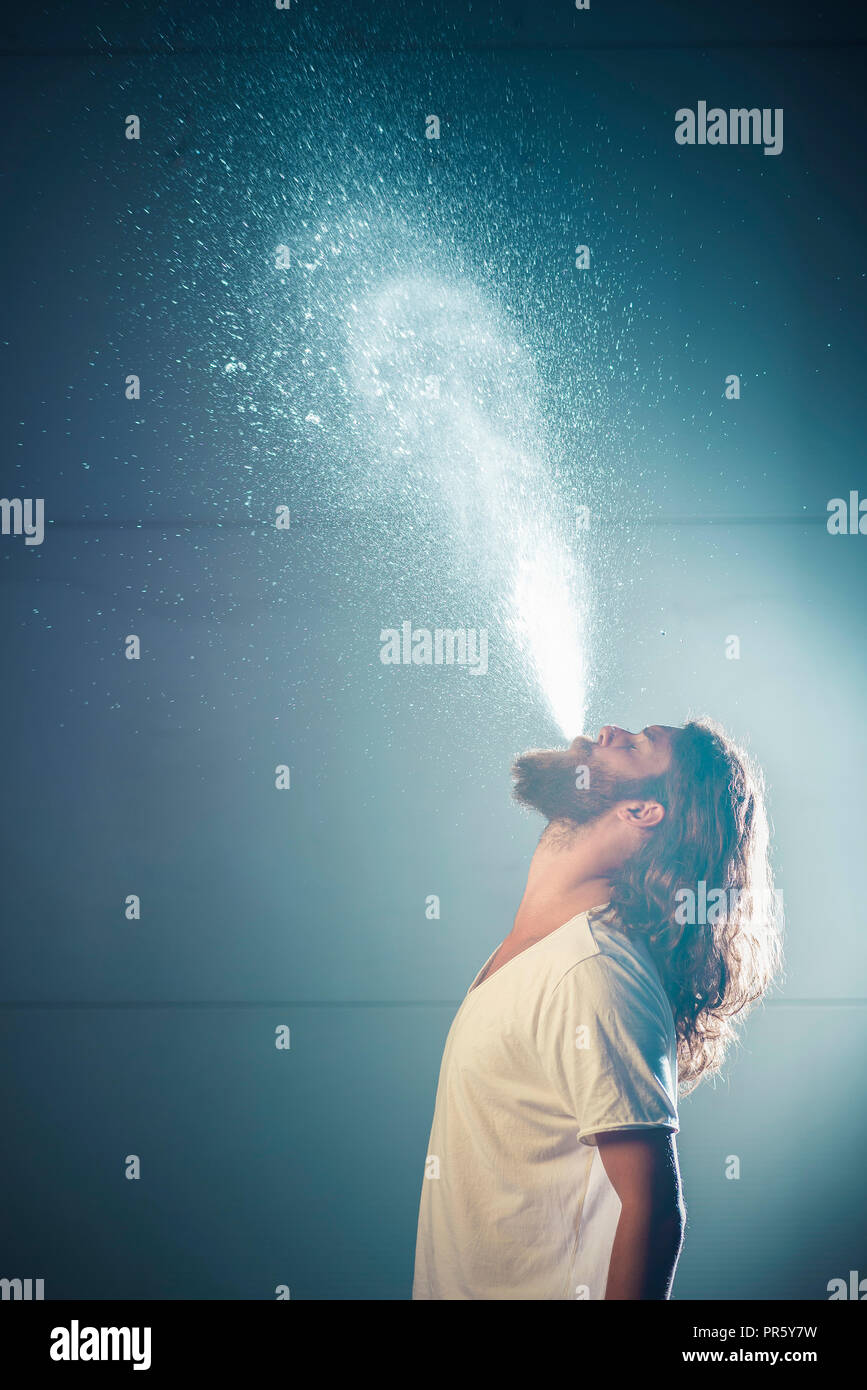Junger Mann bläst das Wasser aus dem Mund Side Shot Stockfoto
