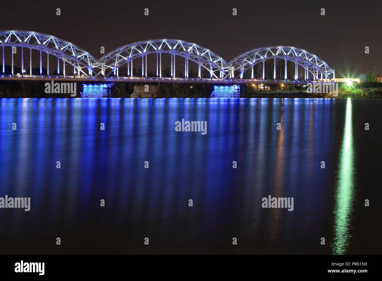 Eisenbahn Brücke überquert den Fluss Daugava in Riga (Lettland) in der Nacht. Letten feiert 100 Jahre Unabhängigkeit während des ganzen Jahres 2018. Stockfoto