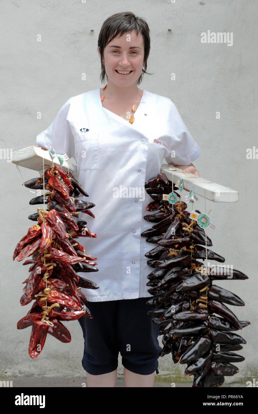Frau mit hängenden Streifen von getrockneten hot Chilies in Espelettes Frankreich Baskenland Europa Stockfoto