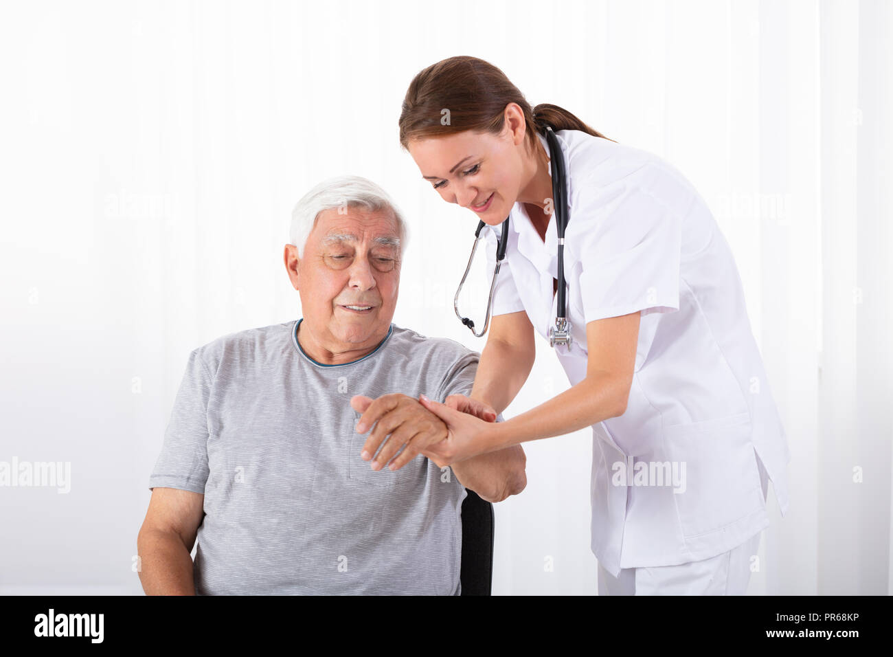 Junge Ärztin Prüfung von männlicher Patient Puls in der Klinik Stockfoto Junge Ärztin Prüfung von männlicher Patient Puls in der Klinik Stockfoto