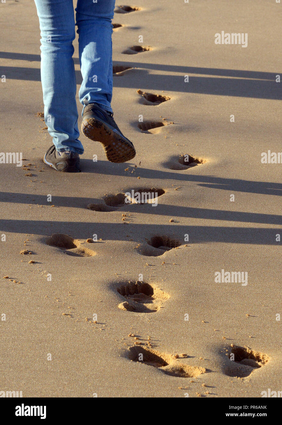 Waliking auf nassen Strand verlassen Footprints Stockfoto