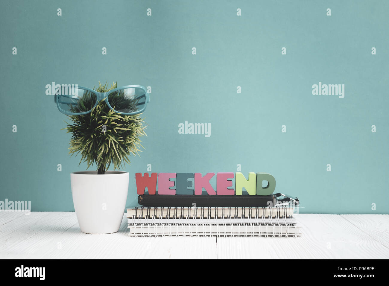Wochenende Buchstaben text und Notebook Papier und wenig Deko Baum in weiße Vase auf hölzernen Hintergrund, hallo Wochenende Urlaub Konzept Idee. Stockfoto
