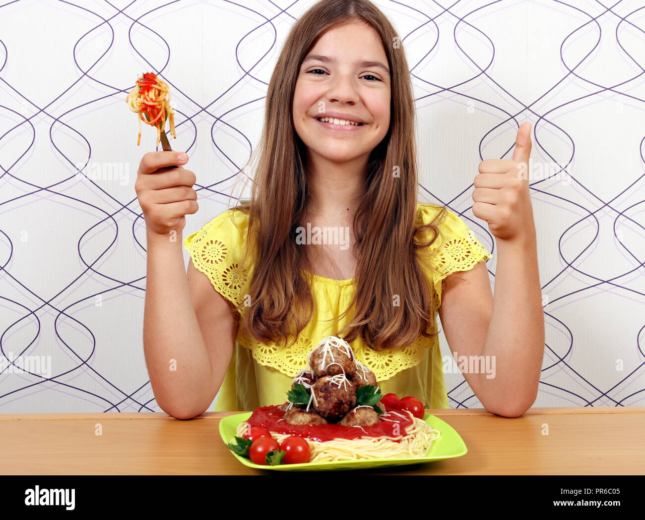 Glückliches Mädchen mit Frikadellen und Spaghetti und Daumen hoch Stockfoto