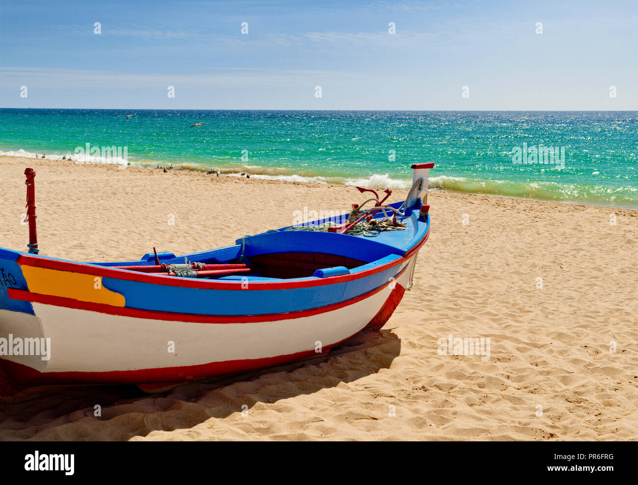 Fischerboot in traditionellen Farben gemalt, auf Armação de Pera am Strand Stockfoto