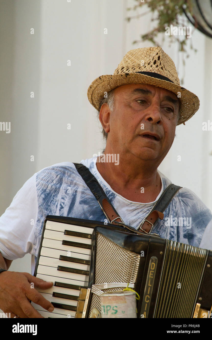 Gaukler spielen Akkordeon für Tipps vor einer Bar in Fiskardo, Kefalonia, Griechenland Stockfoto