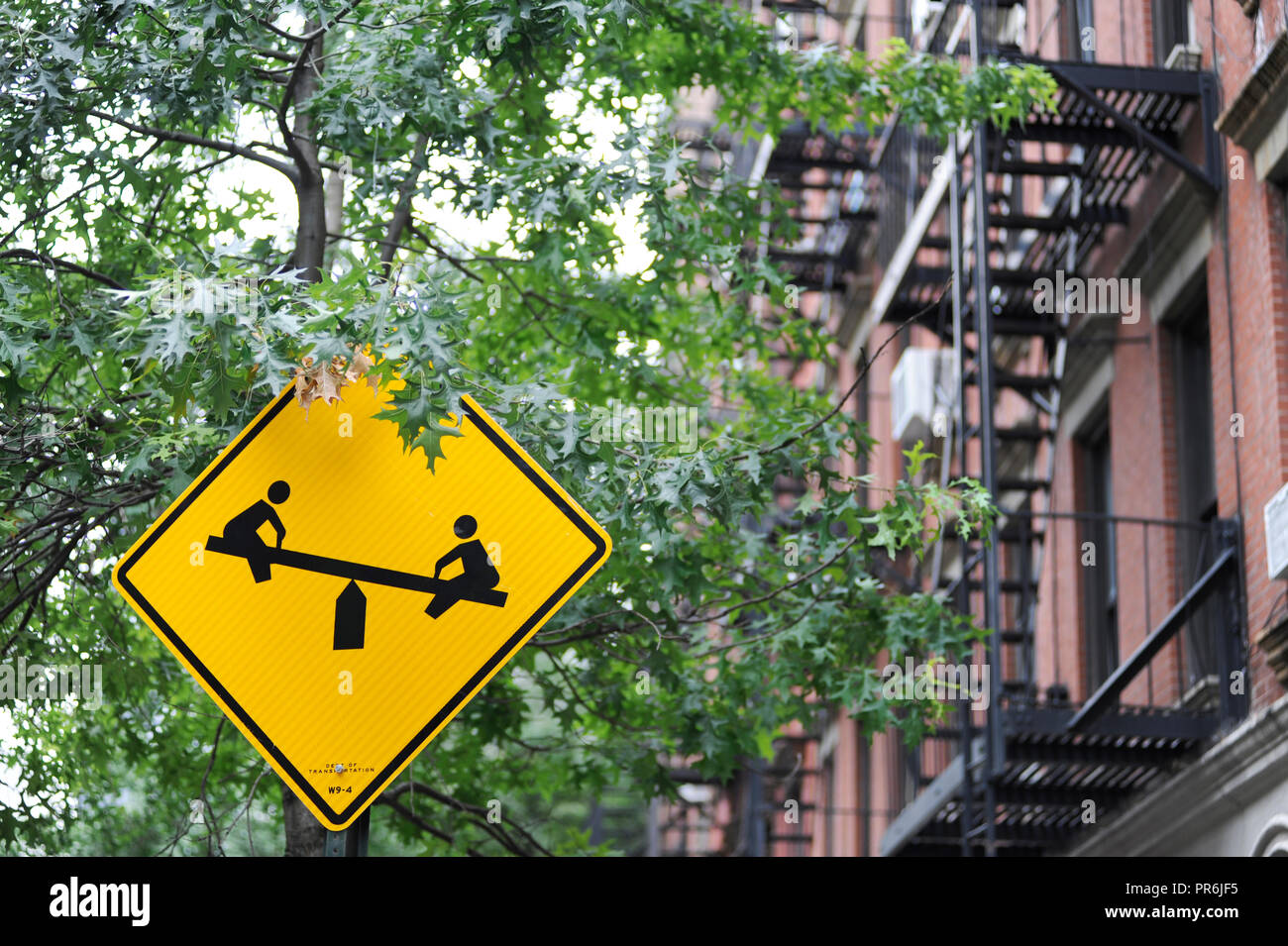 Die gelben Straßenschild mit Kindern im Dorf Manhattan NYC USA spielen Stockfoto