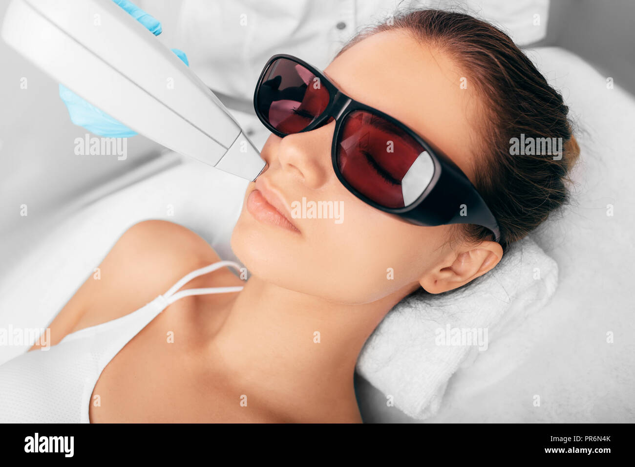 Junge Frau empfangen underarm Laserepilation auf dem Gesicht Stockfoto