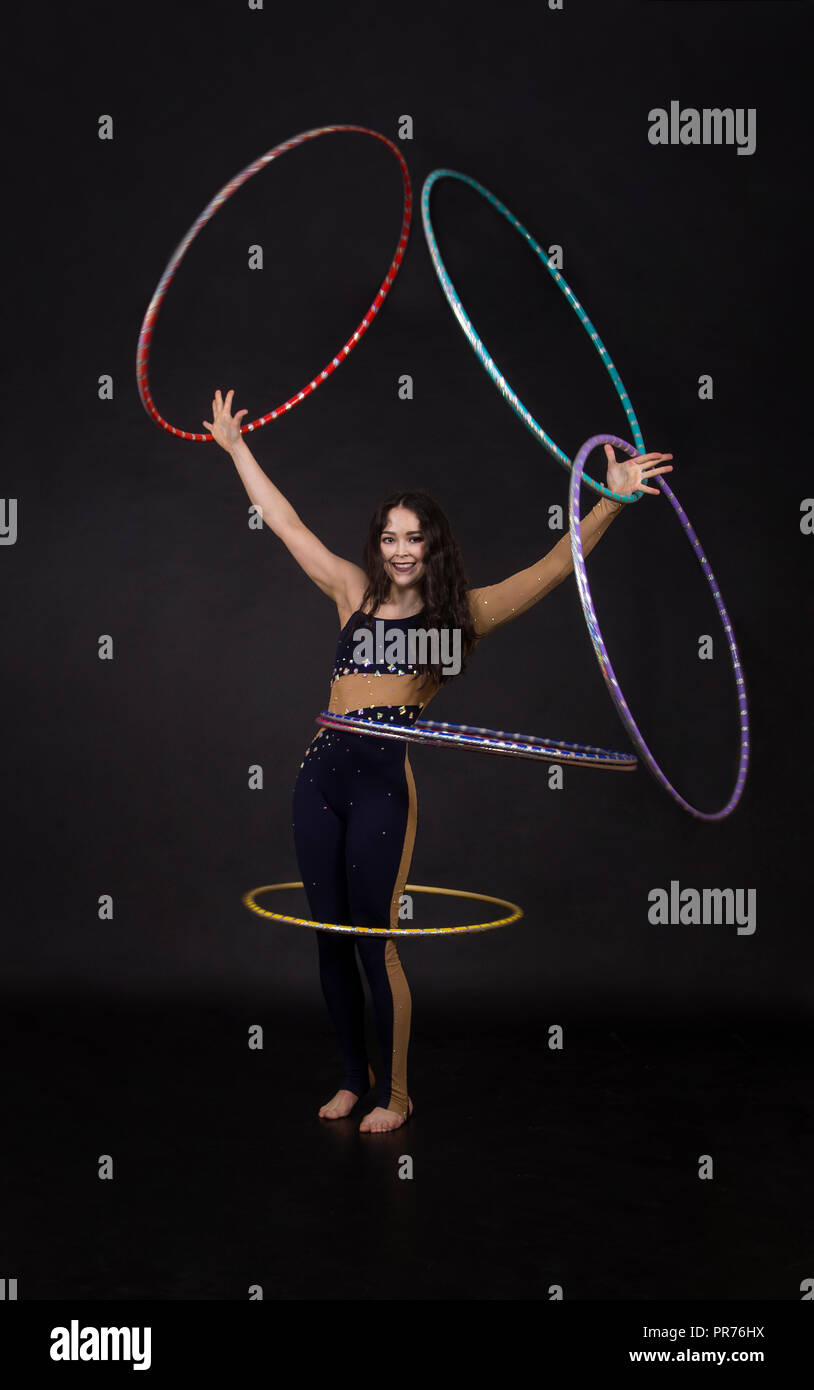 Gymnastische Übungen mit Hula-Hoop Frau führt Zirkus Performer in einem künstlerischen Kostüm. Studioaufnahmen vor dunklem Hintergrund. Stockfoto