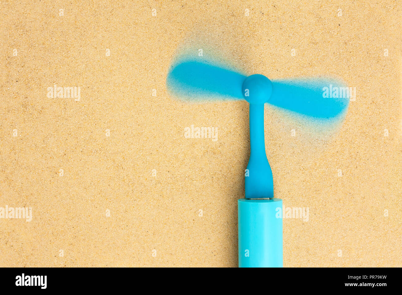 Die blauen tragbarer Ventilator ist in der blauen Power Bank und liegt auf dem Sand eingefügt. Ansicht von Oben. Stockfoto