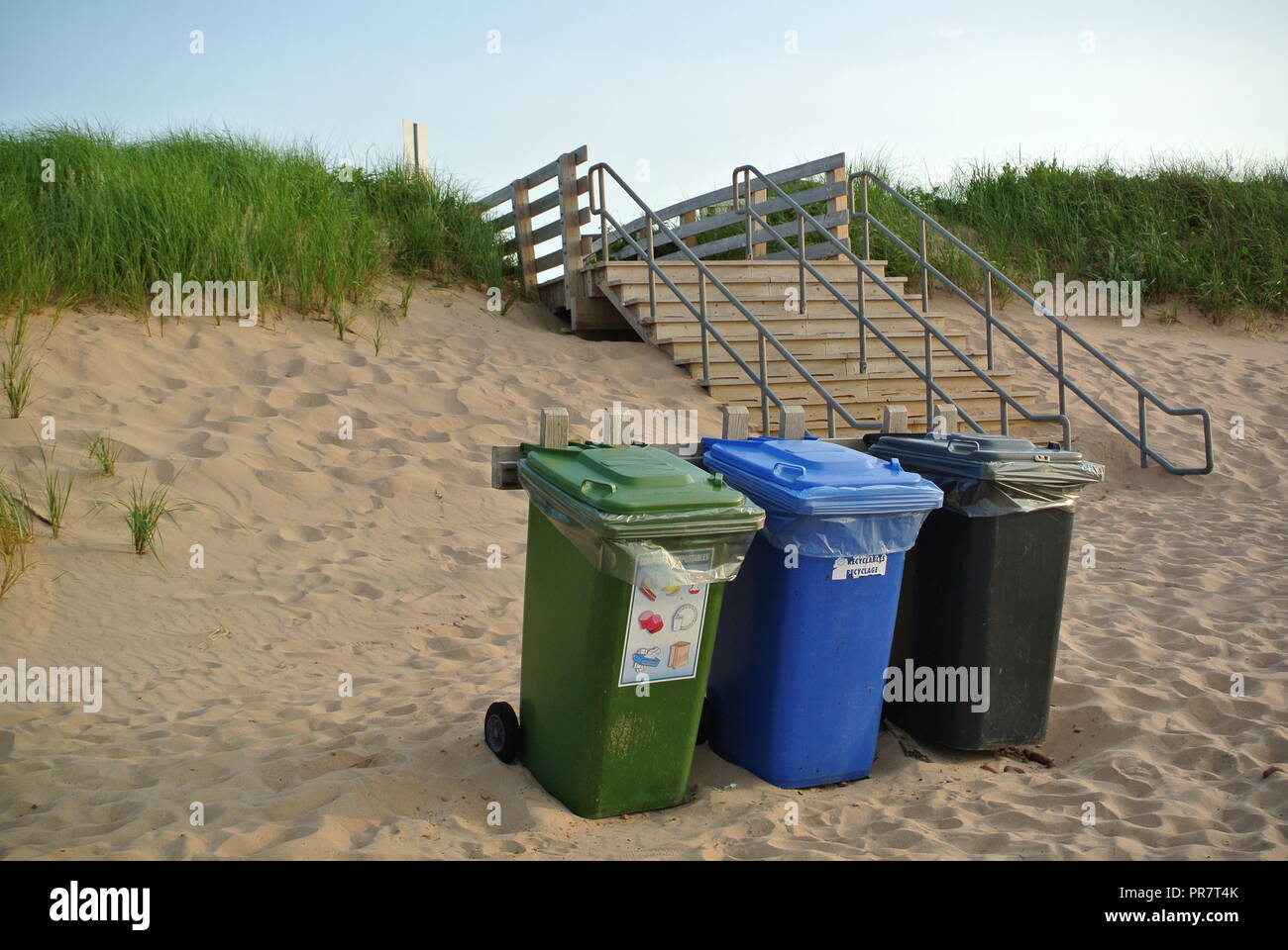 Recycling, Abfall und organics Abfalltonnen in drei Farben grün, blau und schwarz auf einem roten Sandstrand, enrance, Greenwich Nationalpark, PEI. Kanada Stockfoto