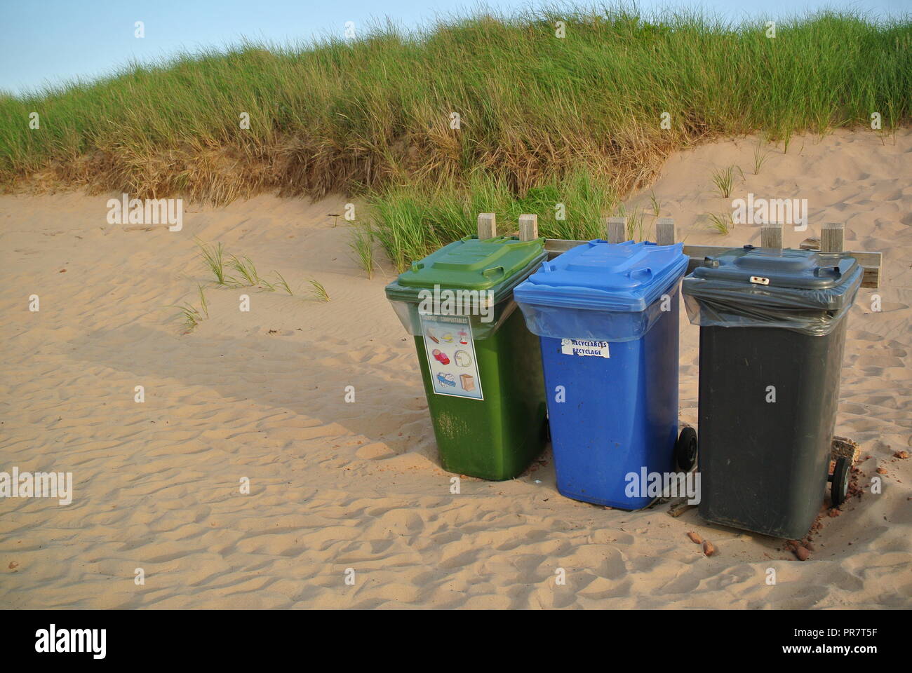 Recycling, Abfall und organics Abfalltonnen in drei Farben grün, blau und schwarz auf einem roten Sandstrand bei Greenwich Nationalpark, PEI. Kanada Stockfoto