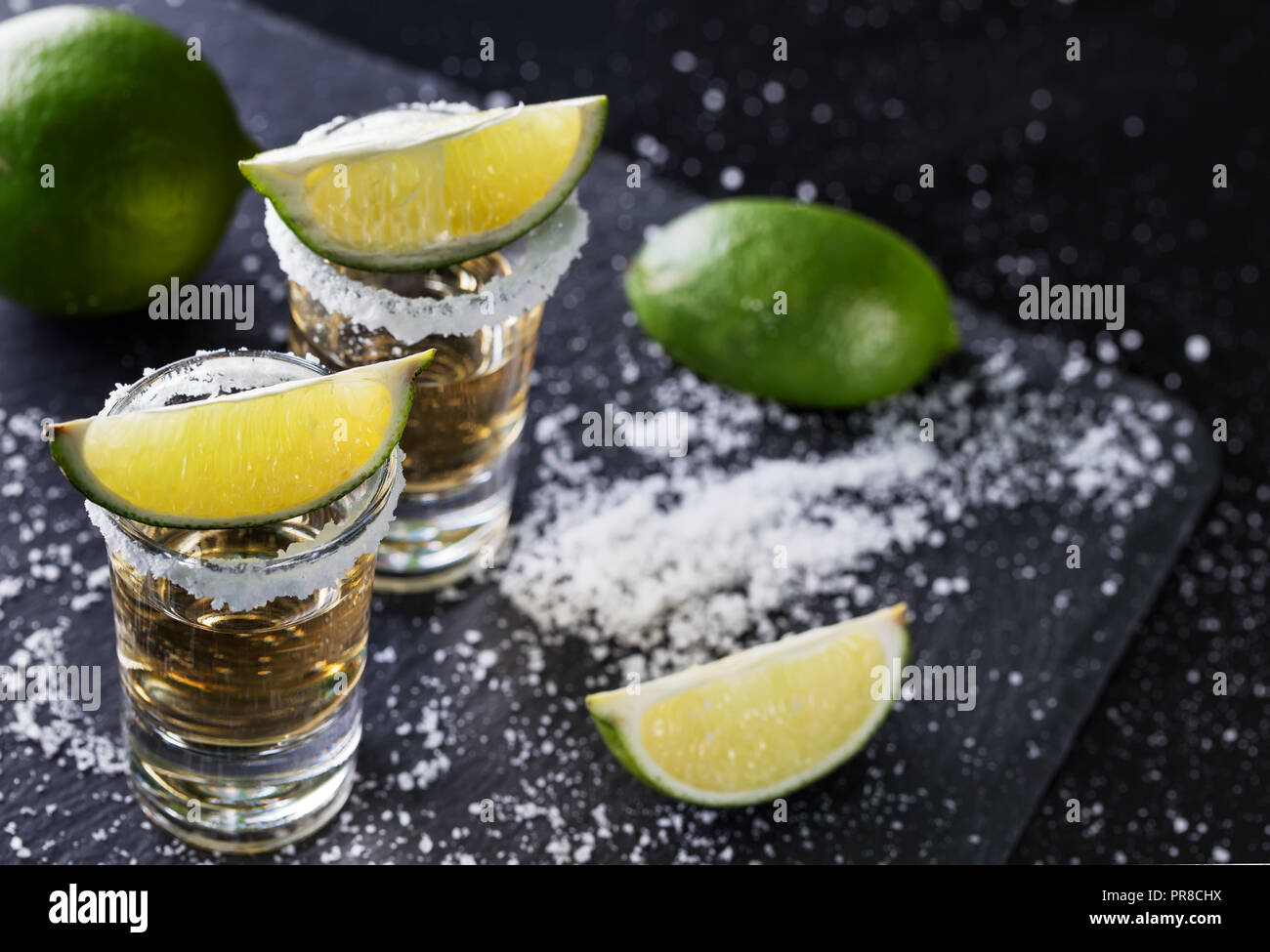 Tequila mit in Scheiben geschnittenen und ganze Kalk und Salz auf einem schwarzen Hintergrund. Alkoholfreien Cocktail. Mexikanische traditionelle Getränk Stockfoto